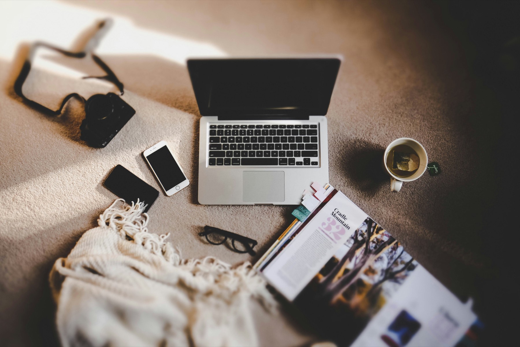 A laptop, phone, notebook and coffee spread across a desk.