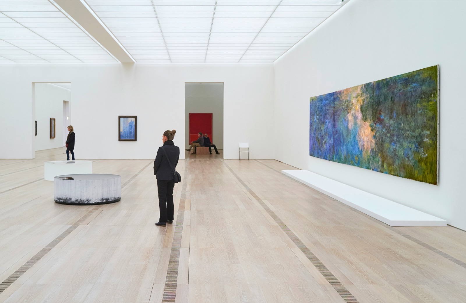 A visitor standing in front of a large painting in a bright gallery.