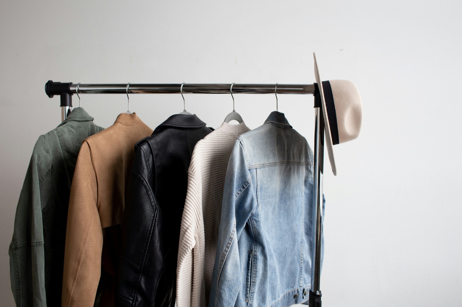 A rail of jackets and coats with a hat hooked over the end.